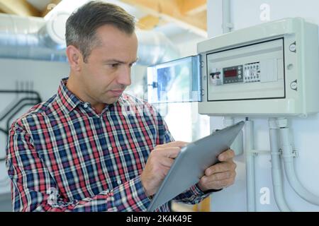 Techniker an der elektronischen Tafel, die das Tablet hält Stockfoto