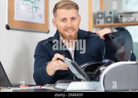 Hübscher junger Mann, der Fotokopierer bedient Stockfoto