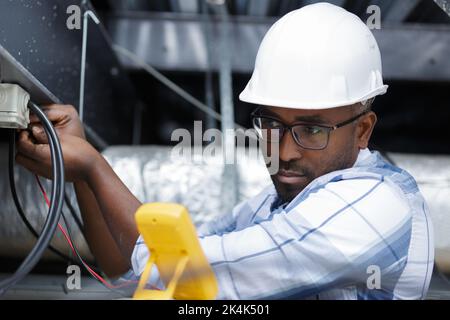 Elektriker die Messung der Spannung der Kabel an der Decke im Innenbereich Stockfoto