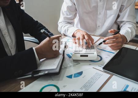 Unternehmer oder Buchhalter arbeiten mit Zeigegraphen Diskussion und Analyse Datendiagramme und Grafiken und mit einem Taschenrechner Zahlen zu berechnen. Unternehmen Stockfoto