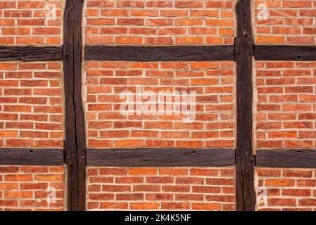 Hintergrundbild mit einer Fachwerkwand aus braunen Holzbalken, gefüllt mit roten Ziegelsteinen Stockfoto