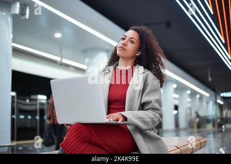 Bloggerin plaudert mit ihren Anhängern, während sie auf einer Bank in der U-Bahn sitzt. Stockfoto