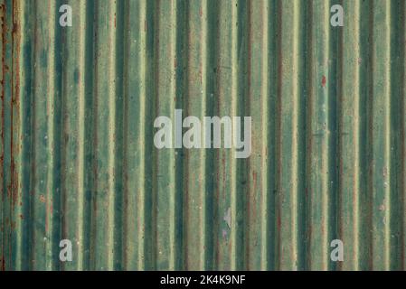 Industrielle Hintergrundtextur, zeigt ein verwittertes Wellblech-Tor mit Rost und abblätternder grüner Farbe Stockfoto