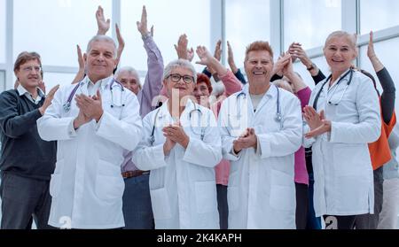 Ärzte und eine Gruppe reifer Menschen applaudieren Stockfoto