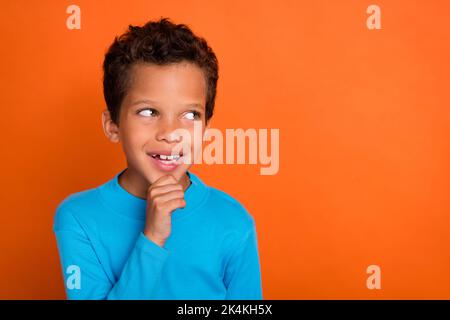 Foto von clever gesinnten Jungen interessiert suchen leeren Raum treffen Wahl Entscheidung Traum Stellen Sie sich isoliert auf orangen Hintergrund Stockfoto