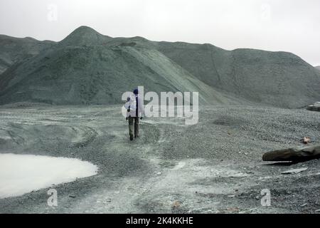 Der einträchtige Mann, der am Honister Slate Quarry vorbei an Verderbhaufen vorbeigeht, führt zu den Wainwright „Grey Knotts“ im Lake District National Park, Cumbria, England. Stockfoto