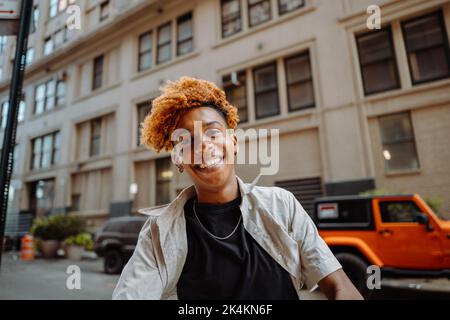 Überfröhlicher Teenager mit gemischtem Rennen, der Freistil-Tanz im Freien in der Straßenwand aufführt und Spaß hat Stockfoto