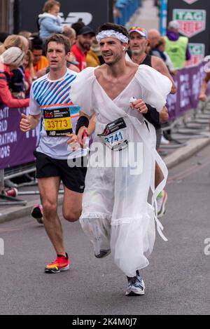 Jordan Maddocks läuft beim TCS London Marathon 2022, an der Tower Bridge Approach Road, City of London, Großbritannien, und trägt ein Brautkleid Stockfoto