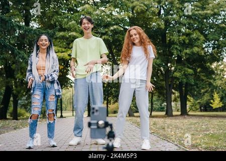 Social Influencer, die Online-Inhalte für ihren Kanal erstellen und im Stadtpark tanzen. Menschen und Technologie. Junge Gruppe Blogger. Web-Beeinflusser Stockfoto