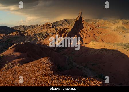 Scharfe Felsformationen und dramatischer Sonnenuntergang am farbenfrohen Skazka Fairyale Canyon in Issyk-Kul Region, Kirgisistan Stockfoto