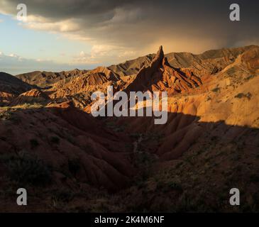 Scharfe Felsformationen und dramatischer Sonnenuntergang am farbenfrohen Skazka Fairyale Canyon in Issyk-Kul Region, Kirgisistan Stockfoto