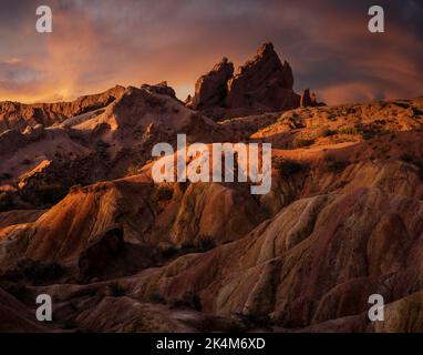 Scharfe Felsformationen und dramatischer Sonnenuntergang am farbenfrohen Skazka Fairyale Canyon in Issyk-Kul Region, Kirgisistan Stockfoto