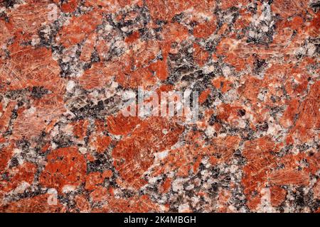 Struktur aus roten Granitfliesen aus nächster Nähe. Natur Granit Textur Hintergrund. Polierter Schmuckstein für Fotodesign. Makro rot grau Granit dekorative Ti Stockfoto