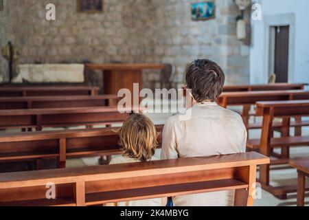 Christian Papa erzählt seinem Sohn biblische Geschichten über Jesus in kirk sitzen. Glaube, Religionsunterricht, moderne Kirche, Vatertag, väterliche Stockfoto