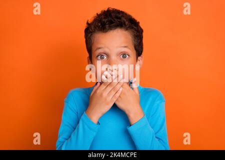 Foto von besorgt Junge Arm Abdeckung Mund nicht sprechen aufhören zu reden shh tragen stilvolle Pullover isoliert auf orangefarbenem Hintergrund Stockfoto