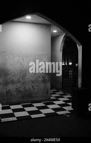 Monochromes Foto eines Raumes mit einem Schachbrett gemusterten Boden in der Cicalengka-Gegend - Indonesien Stockfoto