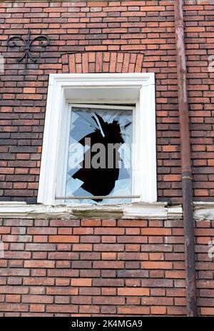 Symbolisches Bild: Verlassen. Leer, Vergangenheit, gebrochen: Einzelnes kaputtes Fenster in Ziegelfassade Stockfoto