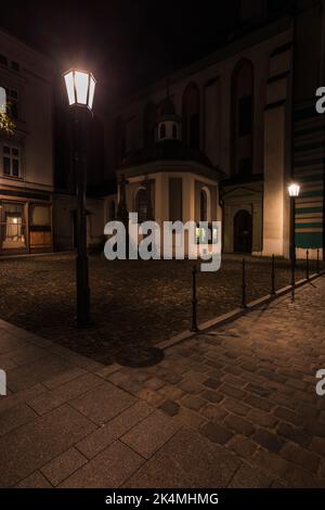 Nachtszene mit Kirche und Straßenlaternen in der Stadt Cieszyn Stockfoto