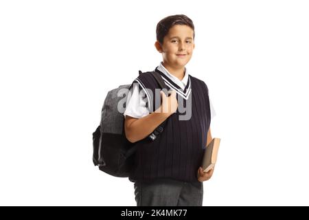 Schuljunge in einer Uniform, hält ein Buch und trägt einen Rucksack isoliert auf weißem Hintergrund Stockfoto