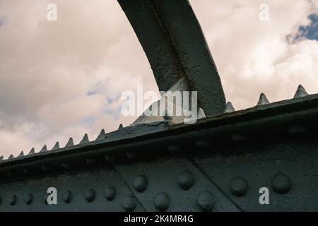 Alte eiserne Fußgängerbrücke Nahaufnahme von vernieteten Metallarbeiten und Trägern Stockfoto