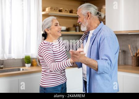 Glückliche Ehepartner. Liebevoller Älterer Ehemann Und Ehefrau, Die Im Kücheninneren Tanzen Stockfoto