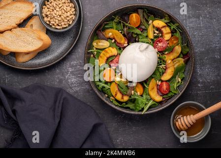 Food Fotografie von Salat mit Burrata, Tomaten, Blättern, gegrilltem Pfirsich Stockfoto