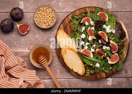 Food-Fotografie von Salat mit Ziegenkäse, Feigen, Blättern, Pinienkernen, Toast, Honig Stockfoto