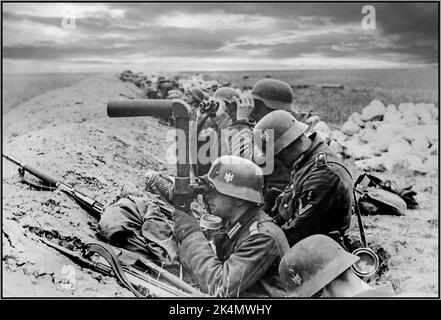 OPERATION BARBAROSSA WW2 Deutsche Infanterie in den Schützengräben der Ostfront beobachtet einer der Soldaten die sowjetischen Positionen mit SF14ZGi Ferngläsern. Eines der einzigartigsten optischen Schlachtfeld-Systeme aus dem Zweiten Weltkrieg, das von Leitz, dem Hersteller der Leica-Kamera, entwickelt wurde. Dieser Hybrid zwischen Fernglas und Periskop ermöglichte es dem Betrachter, sicher verborgen zu bleiben, wobei nur die objektive Linse für den Feind sichtbar war. Die Wehrmacht nutzte sie für die allgemeine Beobachtung (in Fahrzeugen und am Boden) und für die Überwachung und Richtung des Artillerieballes. Datum Oktober 1941 Stockfoto
