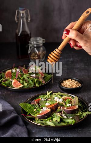 Food-Fotografie von Salat mit Ziegenkäse, Feigen, Blättern, Pinienkernen, Toast, Honig Stockfoto