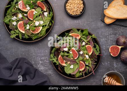 Food-Fotografie von Salat mit Ziegenkäse, Feigen, Blättern, Pinienkernen, Toast, Honig Stockfoto