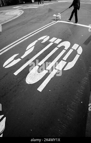 Eine vertikale Aufnahme des Stoppschildes auf der Straße in Schwarz-Weiß Stockfoto