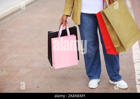 Cropped Portrait von unkenntlich Frau mit bunten Einkaufstaschen auf städtischen Einkaufszentrum Hintergrund. Käufe, Black friday, Rabatte, Verkauf konz Stockfoto