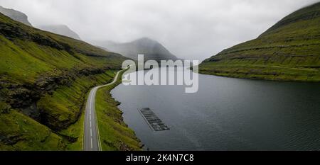 Eine Luftaufnahme einer Autobahn nach Torshavn in der Nähe eines Sees, der von grünen Hügeln auf den Färöer Inseln umgeben ist Stockfoto