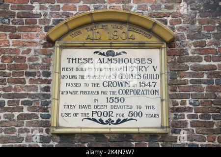 Gedenktafel an den alten Mauern der historischen Almshäuser in Poole. Erbaut im 15.. Jahrhundert widmen sie sich seit 1586 dem Wohlergehen der Armen in Großbritannien. Stockfoto