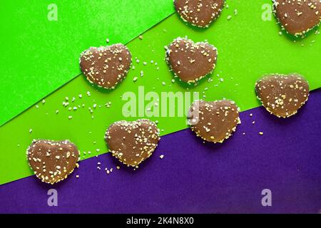 Schokoladenkekse Herzen mit Nüssen auf buntem Hintergrund. Flach auf farbigem Papier. Schokoladenchips Stockfoto