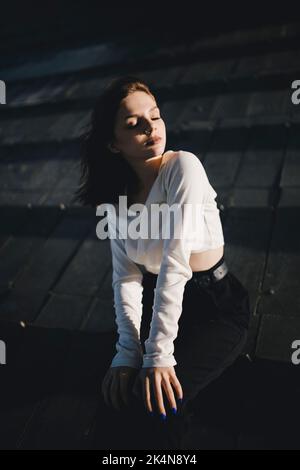 Mädchen in einem weißen Tank Top mit geschlossenen Augen sitzen Stockfoto