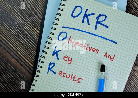 Konzept des OKR - Ziele und Schlüsselergebnisse Schreiben Sie auf ein Buch isoliert auf Holztisch. Stockfoto