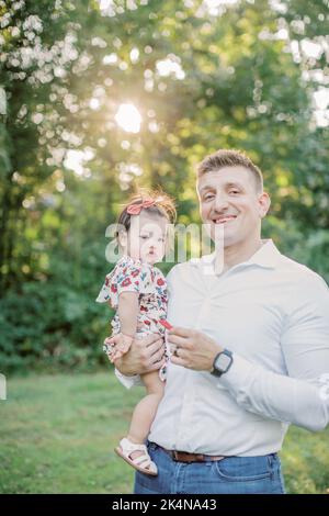 Der kaukasische Vater hält am Sommertag eine 1-jährige Tochter. Stockfoto