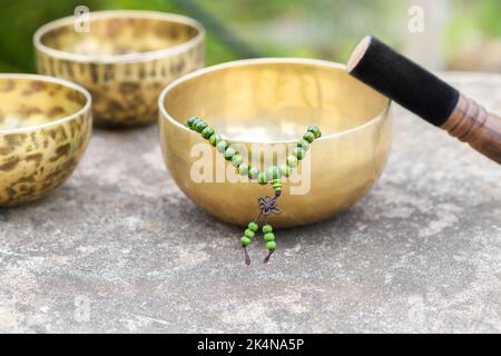 Tibetische Klangschalen mit Stöcken auf grauem Hintergrund im Freien Stockfoto