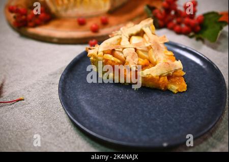 Nahaufnahme eines Stücks klassischer amerikanischer Kürbiskuchen mit knuspriger Kruste, serviert auf einem Marineteller, zum Thanksgiving-Abendessen Stockfoto