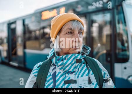 Ältere Frau an der Bushaltestelle im Freien in der Stadt oder Stadt Stockfoto