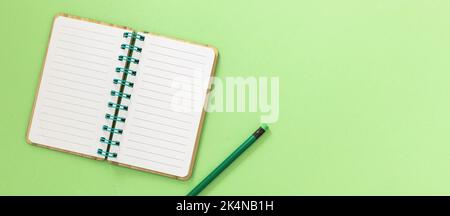 Leerer, offener Spiralnotepad. Notizbuch aus Papier und Bleistift mit Radierer auf hellgrünem Hintergrund. Platz für Text, Overhead-Ansicht Stockfoto