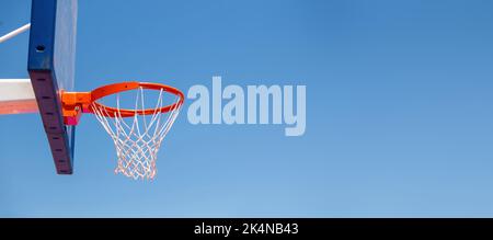 Basketballkorb, roter Ring und Netz auf dem Backboard, klarer blauer Himmel-Hintergrund, Kopierraum. Sonniger Tag, Sportplatz im Freien Stockfoto