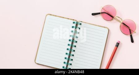 Offenes Tagebuch leeres Papier, Bleistift, Sonnenbrille auf rosa Hintergrund. Leerer spiralförmiger Notizblock, Kopierbereich, Draufsicht Stockfoto
