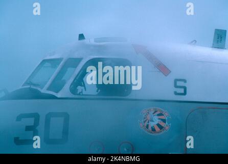 Grumman C-2A Greyhound von VRC-30 bewegt sich auf einem Trägerdeck auf See im Nebel Stockfoto