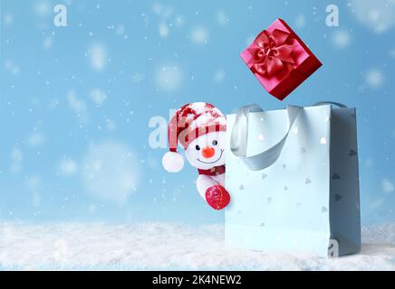 Weihnachts-Schneemann mit Einkaufstasche auf Schnee und Weihnachtsgeschenk. Banner für Winterangebote. Liefergeschenke. Schneemann verschenken Stockfoto