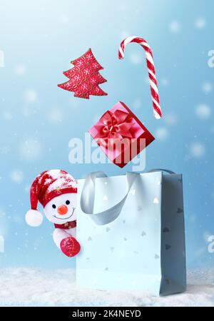 Weihnachts-Schneemann mit Einkaufstasche auf Schnee und Weihnachtsgeschenk. Banner für Winterangebote. Liefergeschenke. Schneemann verschenken Stockfoto