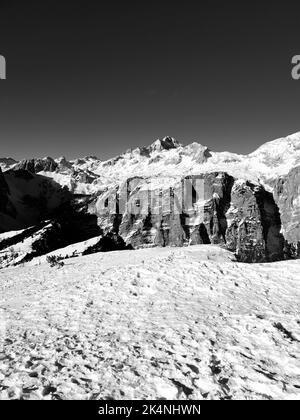 Eine Graustufenaufnahme der schneebedeckten Berggipfel reicht an einem sonnigen Tag Stockfoto