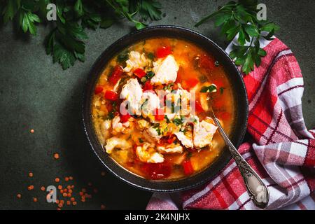 Wärmende Herbstsuppe mit roten Linsen, Hühnerfilet, Gemüse, Gewürzen und Paprika, Gemüsefutter. Grüner Tisch, Draufsicht Stockfoto