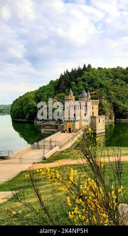 Eine vertikale Aufnahme des Schlosses in Saint Priest la Roche, umgeben von grünen Bäumen und Gras Stockfoto